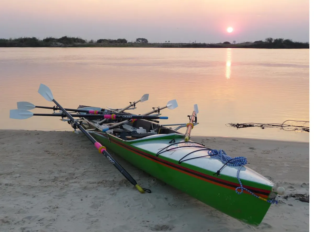 A triple scull pulled up on a sandbank at sunset
